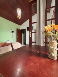 a room with a bed and a table with a vase of flowers at Bora Bora Geribá Kitnet in Búzios +3 photos