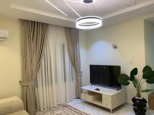 a living room with a flat screen tv and a table at Lushplus Living in Mama