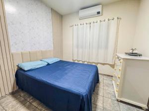 a small room with a blue bed and a window at Casa espaçosa com ar em todos os quartos in Ourinhos