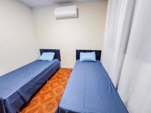 two beds in a room with blue pillows at Casa espaçosa com ar em todos os quartos in Ourinhos