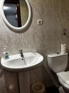 a bathroom with a sink and a toilet and a mirror at Hostal Casa Casado in Belver
