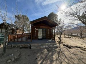 a small cabin with a porch in a field at Boulder Creek RV Resort in Lone Pine