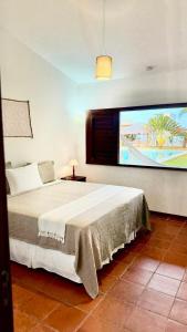 a bedroom with a bed with a large screen at Vila Tao in Fortim
