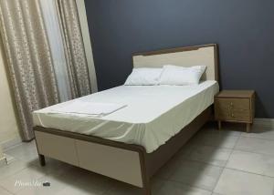 a bed with white sheets and a wooden headboard at Nova apartments in Amdalai