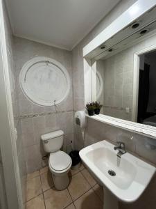 a bathroom with a toilet and a sink and a mirror at BbCasita Blue-Hostal in Santiago