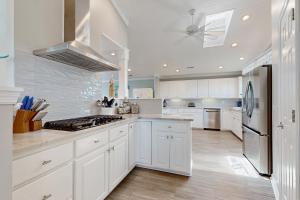 a kitchen with white cabinets and a stainless steel refrigerator at HB303 My Flippin' House in Holden Beach