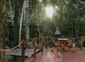 a wooden deck with a table and chairs in the forest at Cabana winchesters - Domo in Cascavel