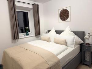 a bedroom with a bed with white sheets and a mirror at Liya Apartments in Aiterhofen