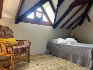 a bedroom with a bed and a chair in a attic at La Villa Terracotta - Vue mer panoramique in Le Diamant