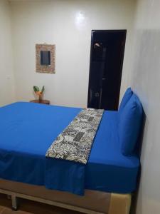 a bedroom with a blue bed and a door at Laguna Hostal Ocean Beach in San Rafael del Sur