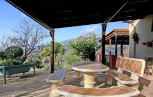 a picnic table and benches on a patio with a mountain at Casa Rural Montion in Jimera de Líbar +21 photos