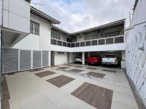 a large building with a parking lot with a red car at Pousada Hospedar Imperial in Campina Grande