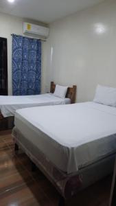 two twin beds in a room with at Laguna Hostal Ocean Beach in San Rafael del Sur