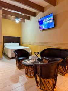 a bedroom with a bed and a tv on the wall at Hotel Real de los Alamos in Álamos