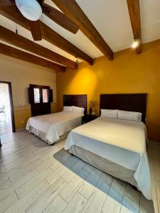 two beds in a room with yellow walls and wooden ceilings at Hotel Real de los Alamos in Álamos +42 photos