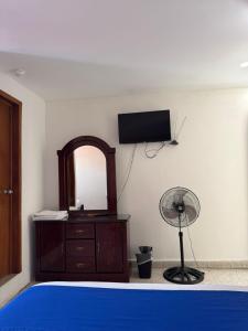 a bedroom with a bed and a fan and a mirror at Hotel Queretaro in Querétaro