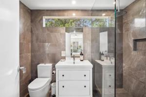 a bathroom with a toilet and a sink and a mirror at Moonah on Mawson in Anglesea +24 photos
