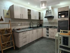 Eine Küche mit weißen Schränken, Spüle und Herd in der Unterkunft Riad Asmaa Agadir in Agadir