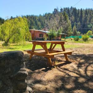 a picnic table in a field with a house in the background at Casa Terra Monoambiente in El Bolsón