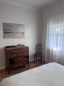 a bedroom with a bed and a dresser and a window at Ocean Breeze Cottage in Umina