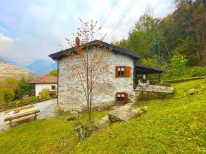 ein kleines Haus auf einem Hügel mit einer Bank in der Unterkunft Chalet Casargo in Casargo