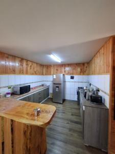 a large kitchen with wooden floors and a wooden table at Habitación privada en Coñaripe de 1 Cama in Coñaripe