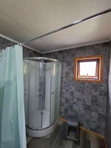 a bathroom with a shower and a window and a stool at Habitación privada en Coñaripe de 1 Cama in Coñaripe +3 photos
