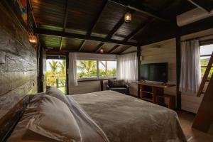 a bedroom with a bed and a desk and a television at Grajagan Surf Resort in Ilha do Mel