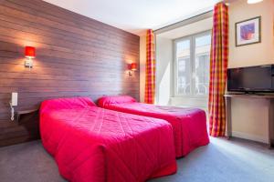 a room with two pink beds and a tv at Hôtel Restaurant La Terrasse in Saugues
