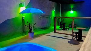 a green room with a table and an umbrella at Pousada navarro in São Gabriel