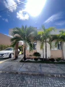 two palm trees in front of a house at Casa 2 quarto em condomínio in Camaçari