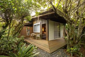 a small house with a wooden deck in the woods at Grajagan Surf Resort in Ilha do Mel