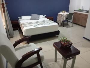 a bedroom with a bed and a chair and a table at Apartaestudio con cocina dentro centro comercial in Cartago