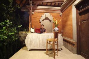 a man sitting at a table with a laptop at Soca Garden Guest house in Ubud