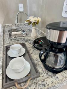a coffee maker on a counter with plates and cups at Pousada 8 Mares in Arraial do Cabo