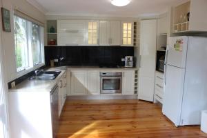 a kitchen with white cabinets and a white refrigerator at Kookas Retreat in Mount Martha