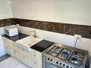 a kitchen with a stove top oven next to a sink at Tranquil Stay Tunereng in Tujering +6 photos
