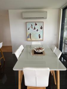a white dining room with a white table and chairs at Gull Apartment in Strahan
