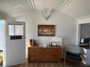 a room with a wooden dresser and a picture on the wall at The Artists Cottage Waterfront Hideaway in Strahan