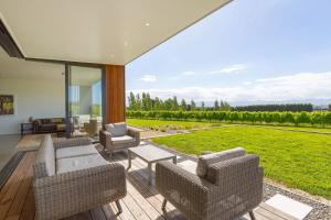 a living room with chairs and a patio with a view at 89 In The Vines in Martinborough