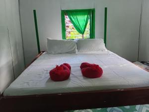 two red shoes sitting on top of a bed at Lamkail beach island bungalow in Lénakel