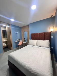 a bedroom with a large bed with a blue wall at Amaranto Suites in Medellín