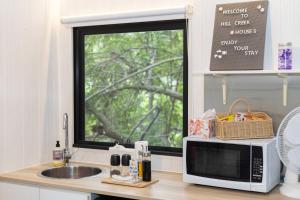 a kitchen counter with a microwave and a window at Hill Creek Tiny House 5 by Tiny Away in Perwillowen