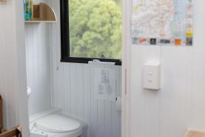 a bathroom with a white toilet and a window at Hill Creek Tiny House 5 by Tiny Away in Perwillowen +11 photos