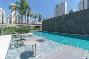 a swimming pool with a bench and a table at Studio Lumière Moema in São Paulo