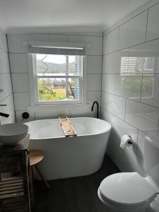 a white bathroom with a tub and a toilet at The Artists Cottage Waterfront Hideaway in Strahan +39 photos
