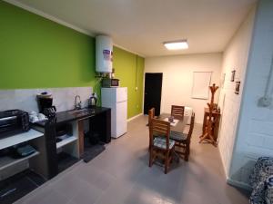 a kitchen with green walls and a table and chairs at Dptos Ceci in Centenario