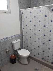 a bathroom with a toilet and a shower curtain at Dptos Ceci in Centenario