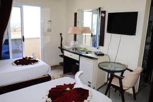 a hotel room with two beds and a desk with a television at Le-Printemps Hotel in Suez +25 photos