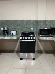 a kitchen with a stove and a microwave at Casa Las Brisas in Nicoya